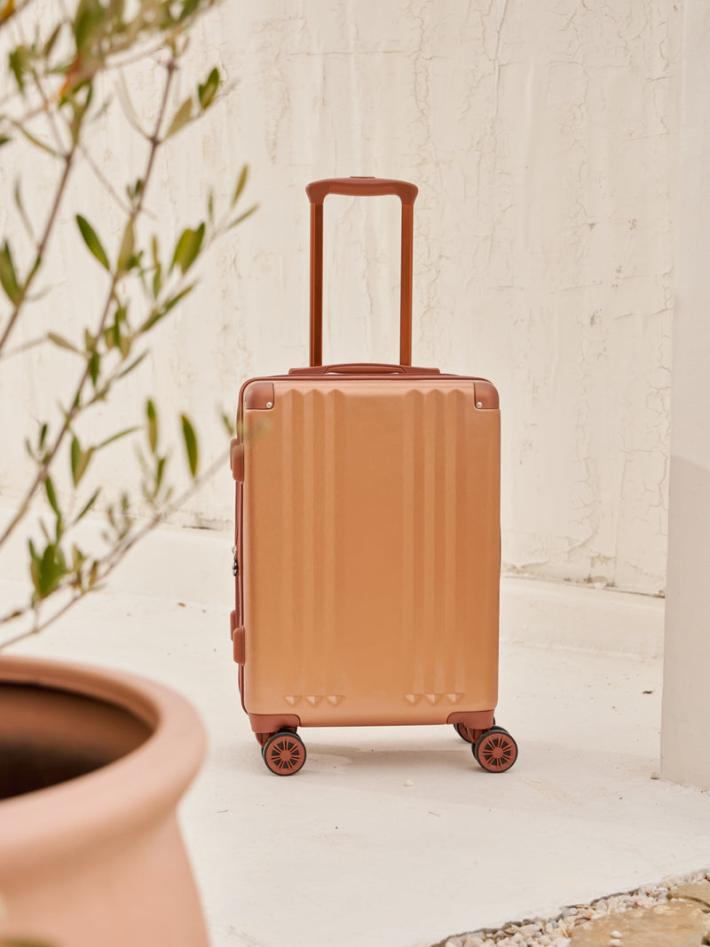 Front-facing image of CALPAK Ambeur carry-on luggage with 360 spinner wheels in copper