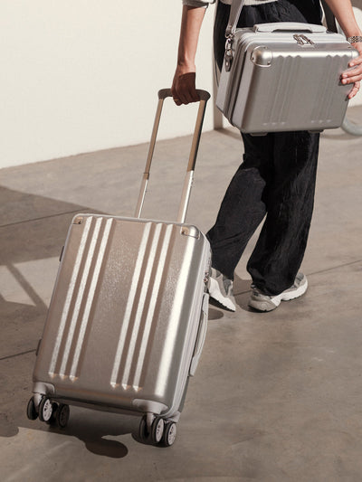 Studio product shot of front-facing lightweight silver CALPAK Ambeur 22-inch hardside rolling spinner carry-on luggage; LAM1020-SILVER view 2