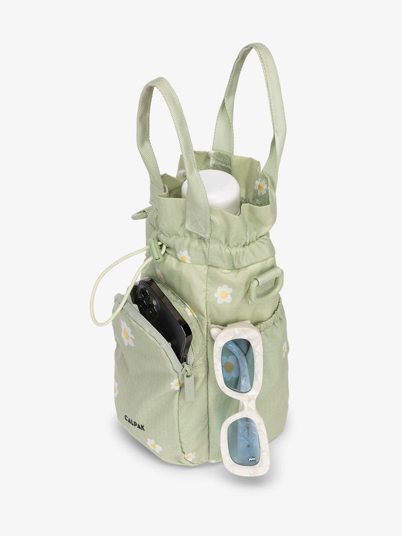 water bottle bag in green with daisy print holding phone and sunglasses