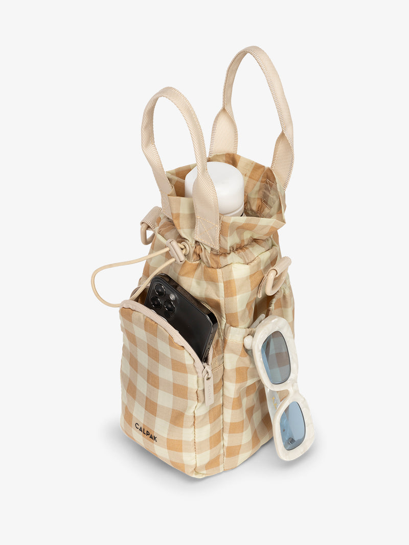 water bottle bag in white and beige gingham print with phone and sunglasses