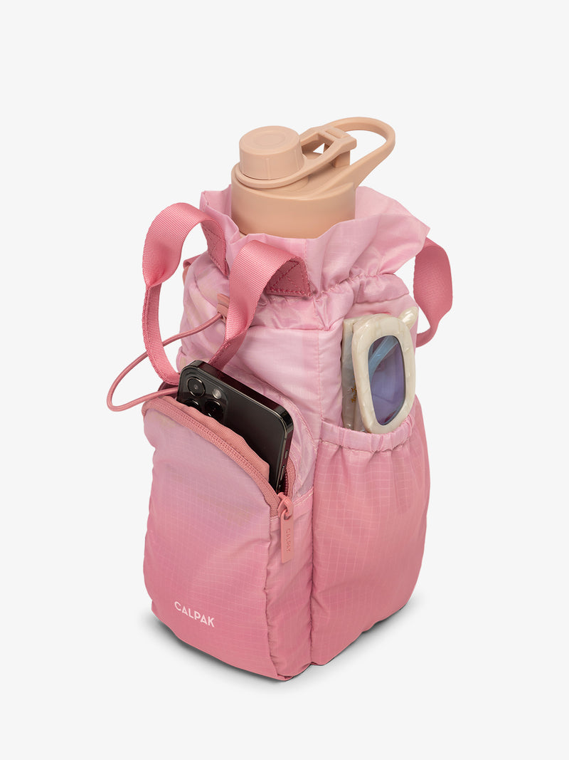 CALPAK Water Bottle Holder in pink ombre Tea Rose with use of front phone pocket, side pocket with sunglasses and water bottle in main compartment