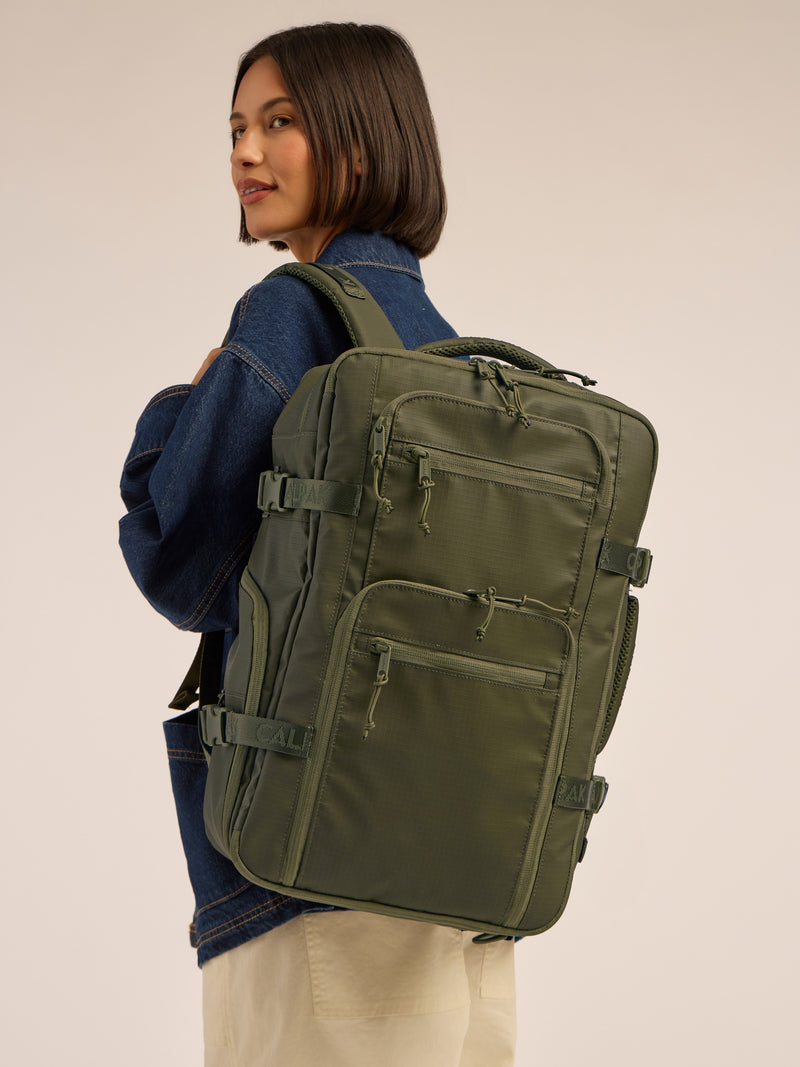 Model wearing the CALPAK Terra 26L Laptop Backpack Duffel in dark green Matte Pine