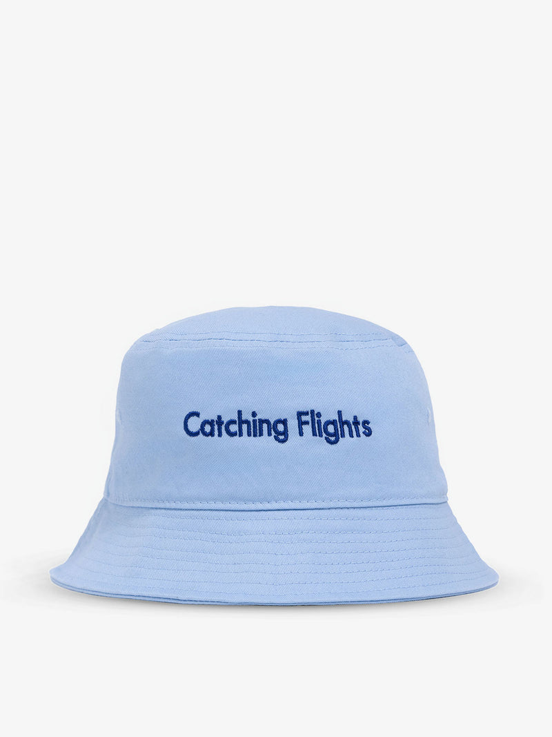 Baby blue CALPAK Bucket Hat with "Catching Flights" text on back