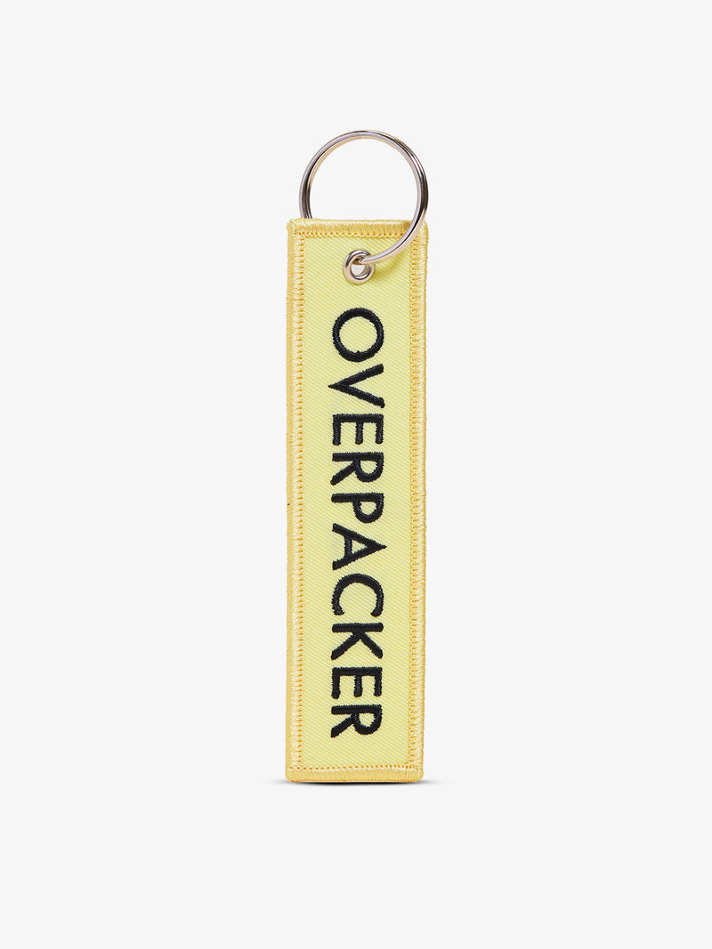 Yellow CALPAK Overpacker Luggage Tag back-view with "OVERPACKER" text