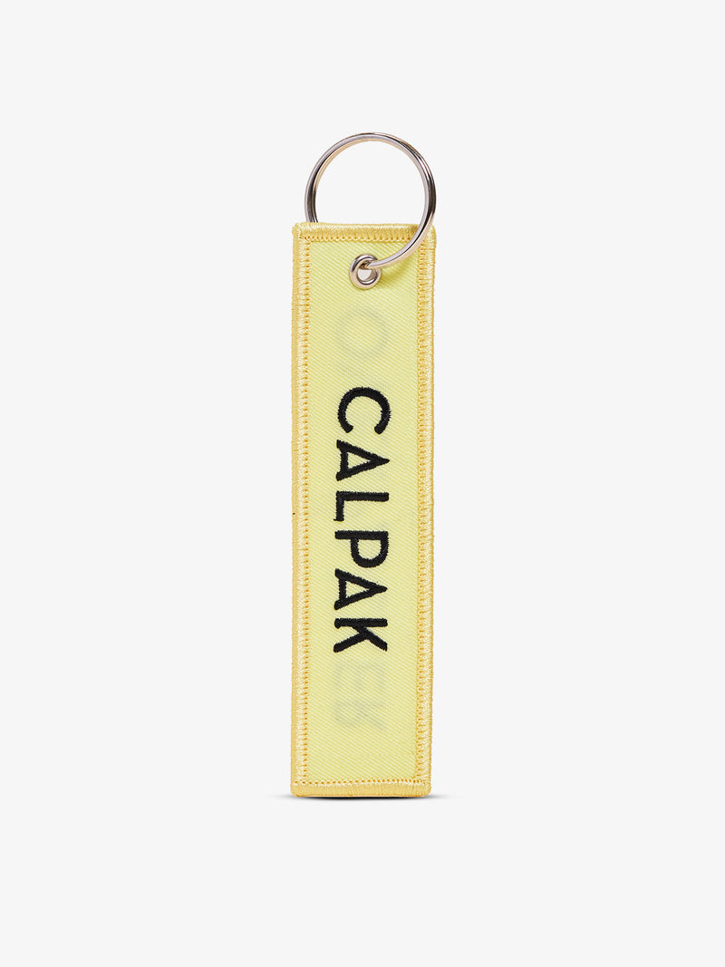 Yellow CALPAK Overpacker Luggage Tag front-view with "CALPAK" text