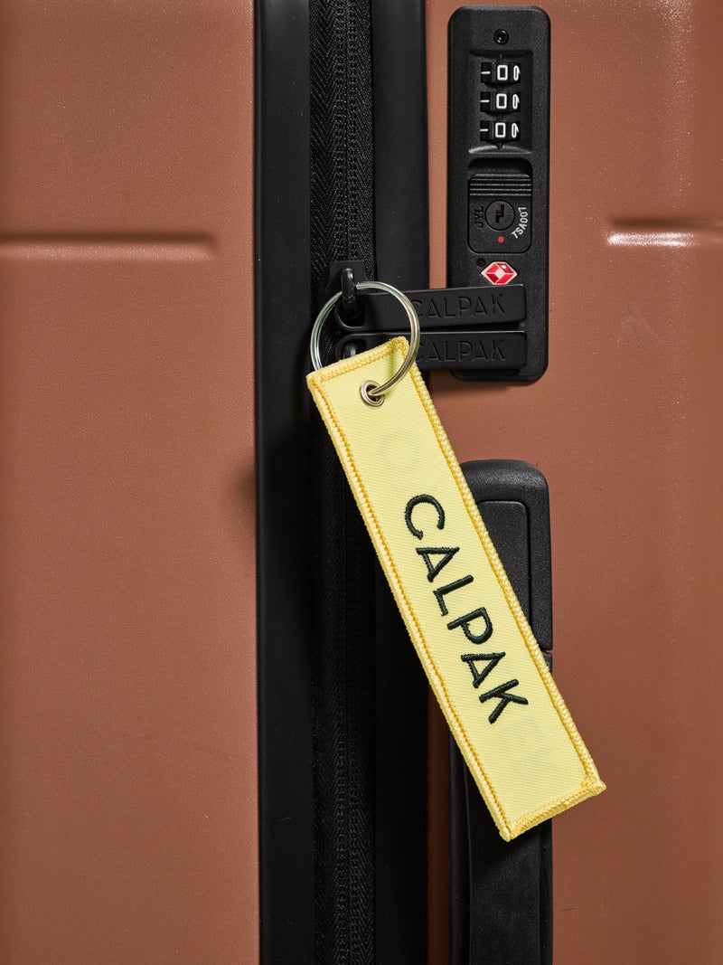 CALPAK Overpacker Luggage Tag attached to Hue Luggage in hazel