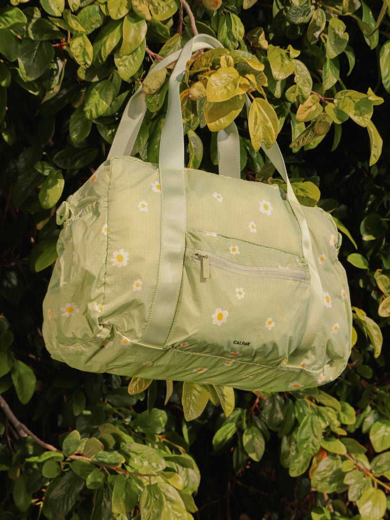 CALPAK Compakt duffel bag with zippered pocket and water resistant fabric in light green daisy print