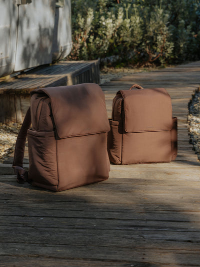 CALPAK Convertible Mini Diaper Backpack attached to stroller by CALPAK Stroller Straps in hazelnut brown; BBPC2401-HAZELNUT, BPC2401-HAZELNUT