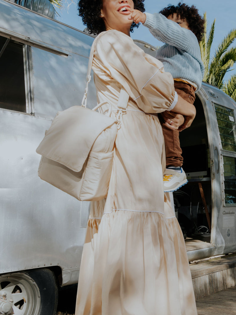 Model wearing CALPAK Convertible MIni Diaper Backpack as crossbody bag in oatmeal