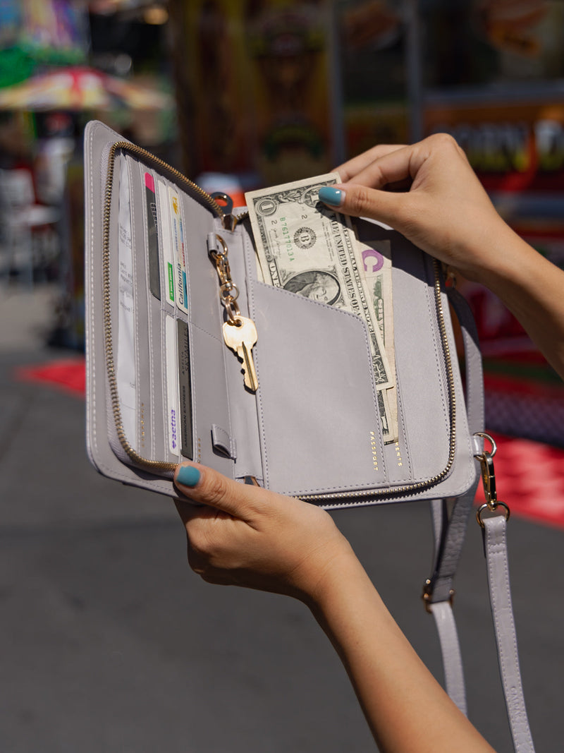 Model displaying interior of CALPAK Croc Wallet in iris gray