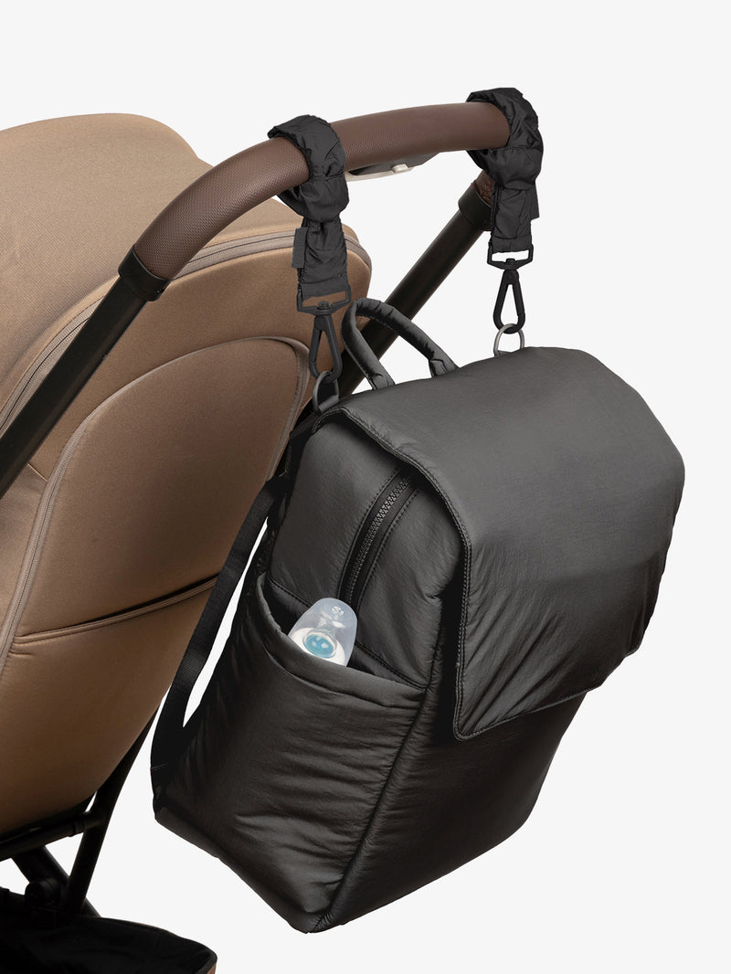 CALPAK Diaper Backpack in Black with Black Stroller Straps attached to a brown stroller