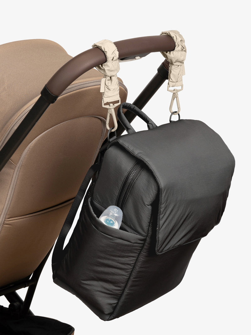 CALPAK Diaper Backpack in Black with white Oatmeal Stroller Straps attached to a brown stroller