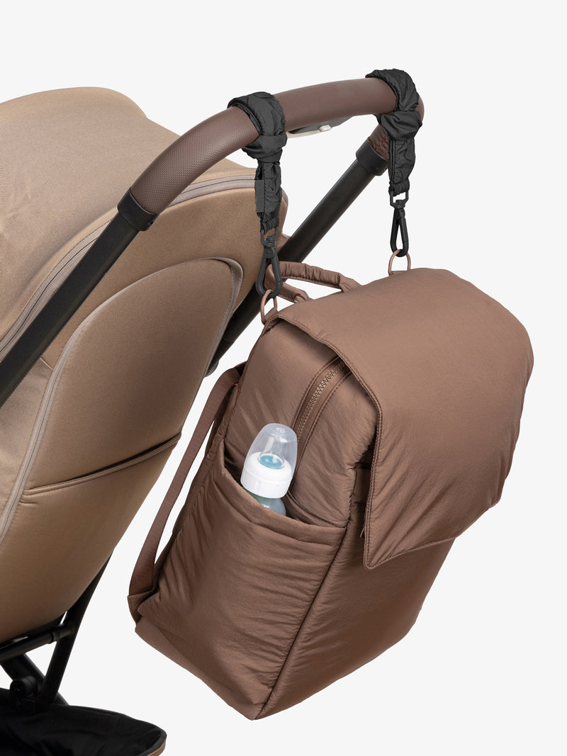 CALPAK Diaper Backpack in brown Hazelnut with Black Stroller Straps attached to a brown stroller