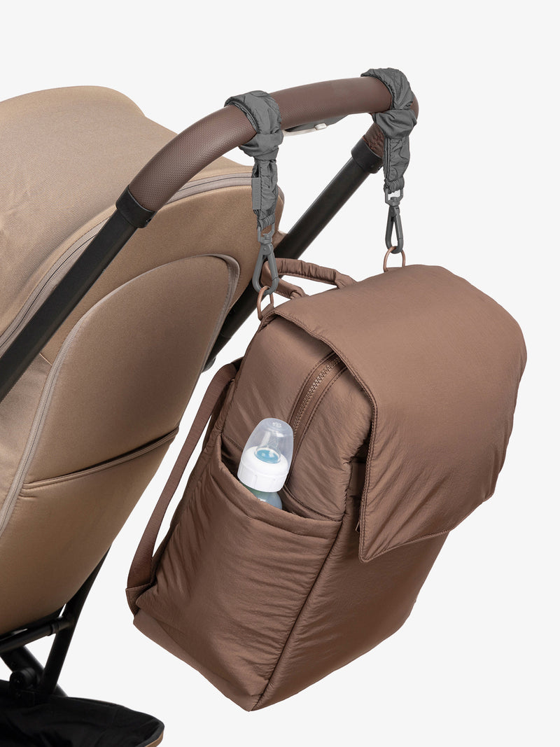 CALPAK Diaper Backpack in brown Hazelnut with grey Slate Stroller Straps attached to a brown stroller