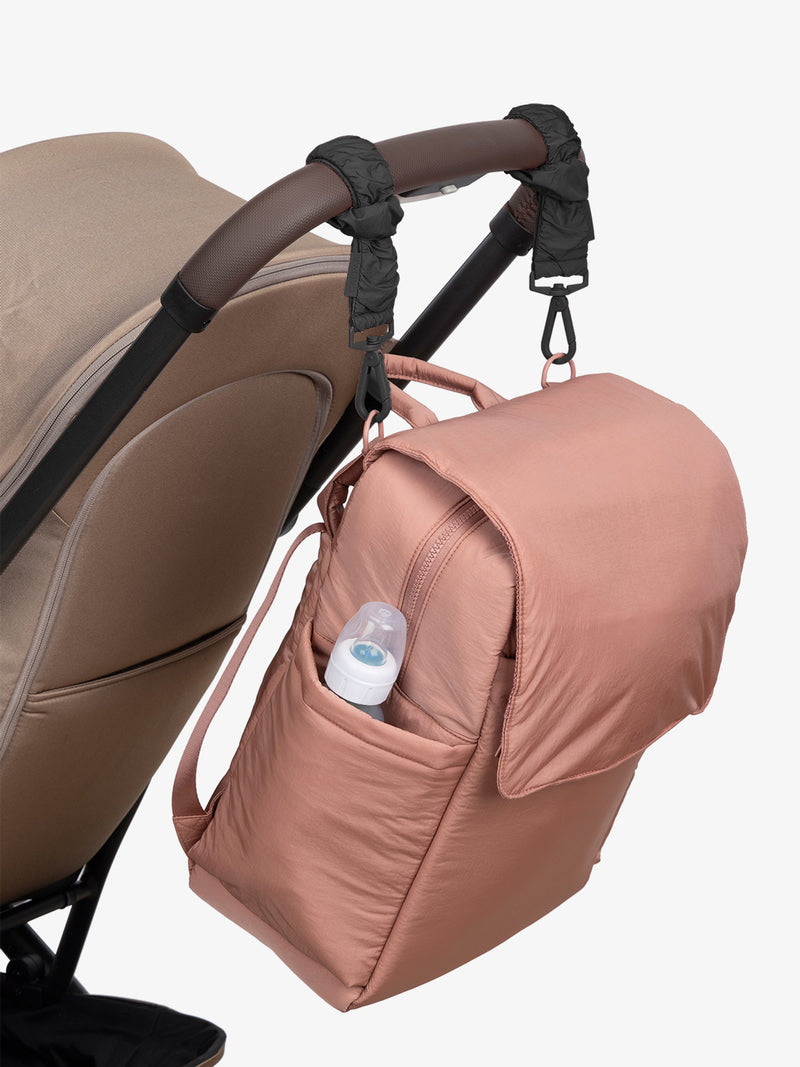 CALPAK Diaper Backpack in pink Peony with Black Stroller Straps attached to a brown stroller