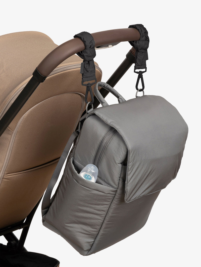 CALPAK Diaper Backpack in grey Slate with Black Stroller Straps attached to a brown stroller