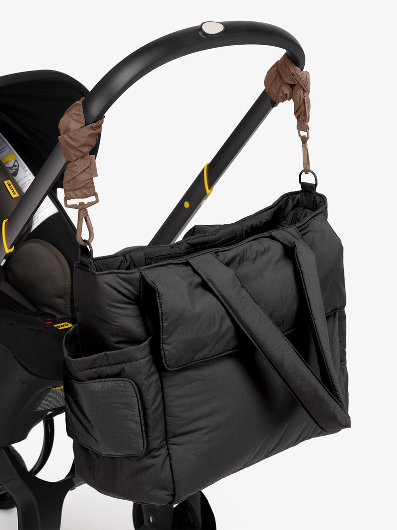 CALPAK Diaper Tote Bag in Black with brown Hazelnut Stroller Straps attached to a black stroller