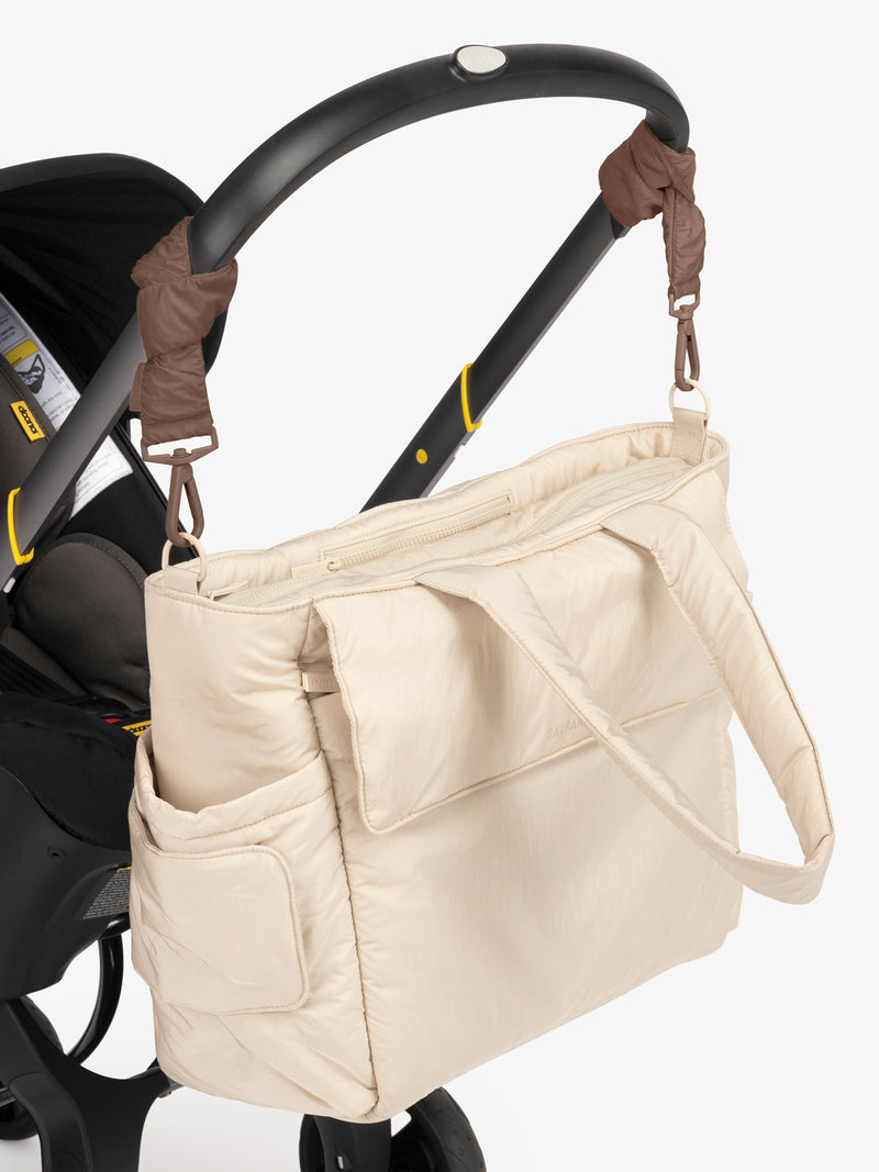 CALPAK Diaper Tote Bag in white Oatmeal with brown Hazelnut Stroller Straps attached to a black stroller