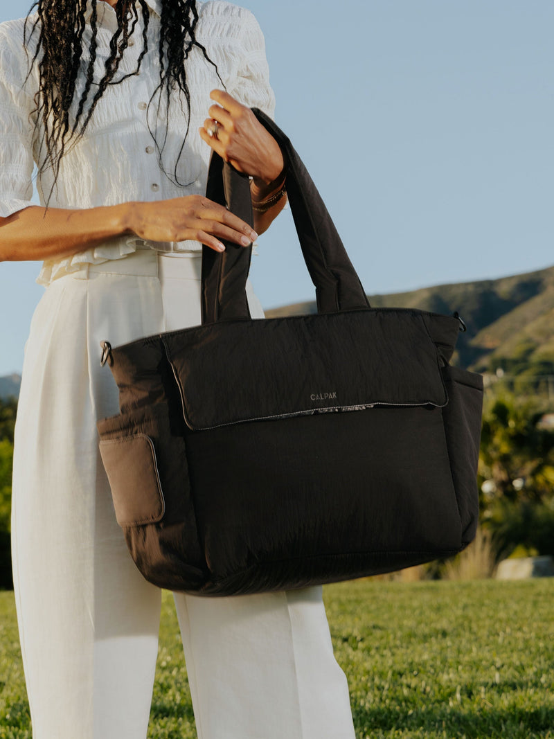 Model displaying CALPAK Diaper Tote Bag with Laptop Sleeve in black