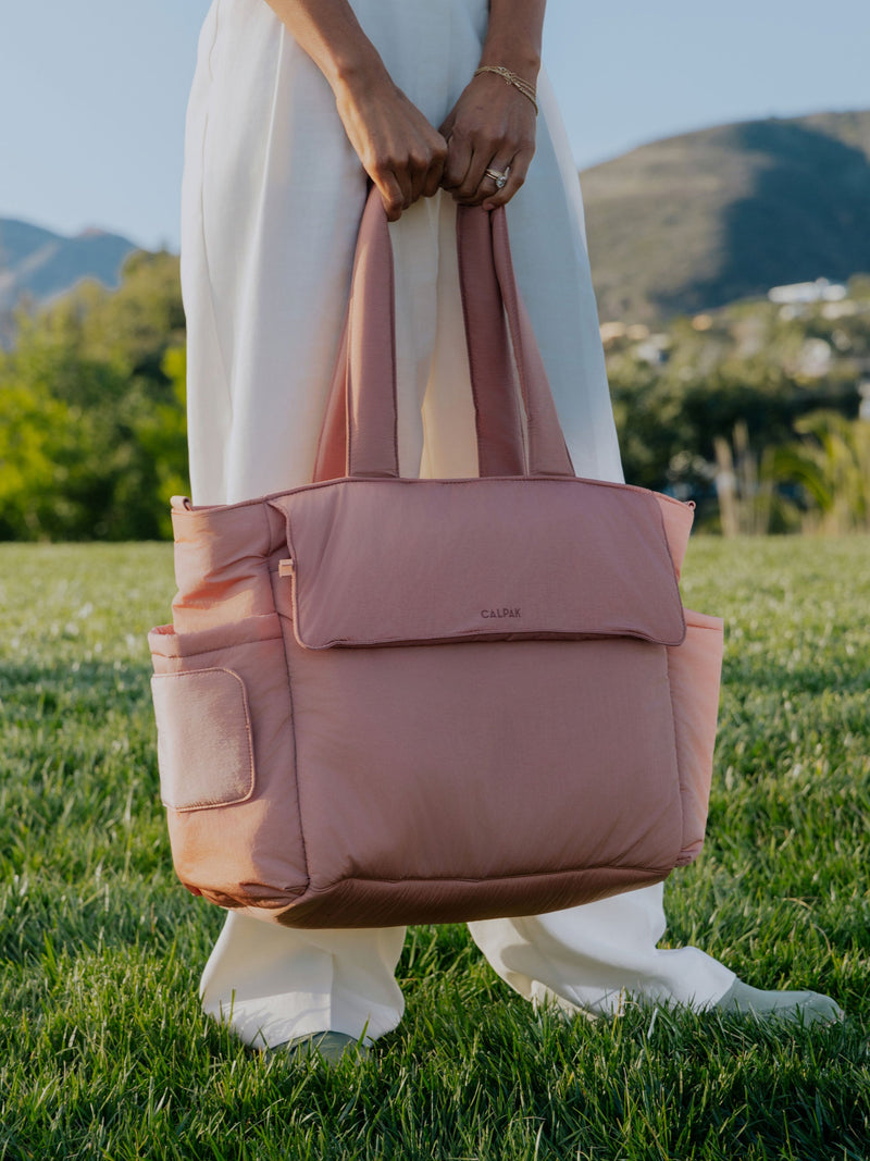 Model holding peony CALPAK Diaper Tote Bag with Laptop Sleeve by handles