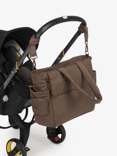 CALPAK Diaper Tote Bag with Stroller Straps attached to stroller handle in brown hazelnut; BTBB2401-HAZELNUT