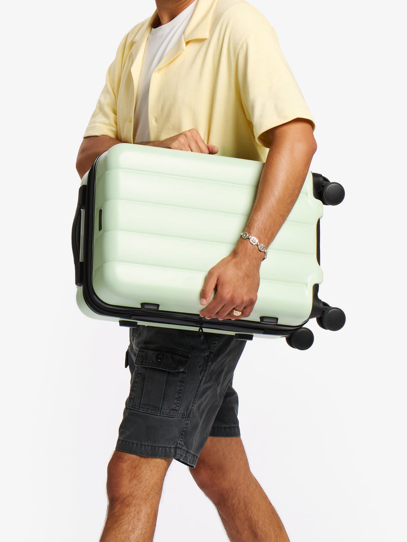 Model holding CALPAK Evry Carry-On Luggage in light green daisy