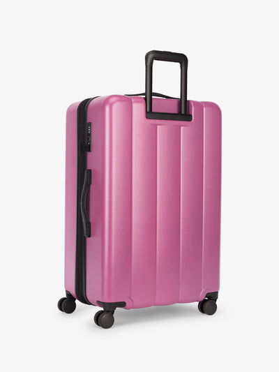 CALPAK large luggage featuring dual spinner wheels and bottom grab handle in raspberry