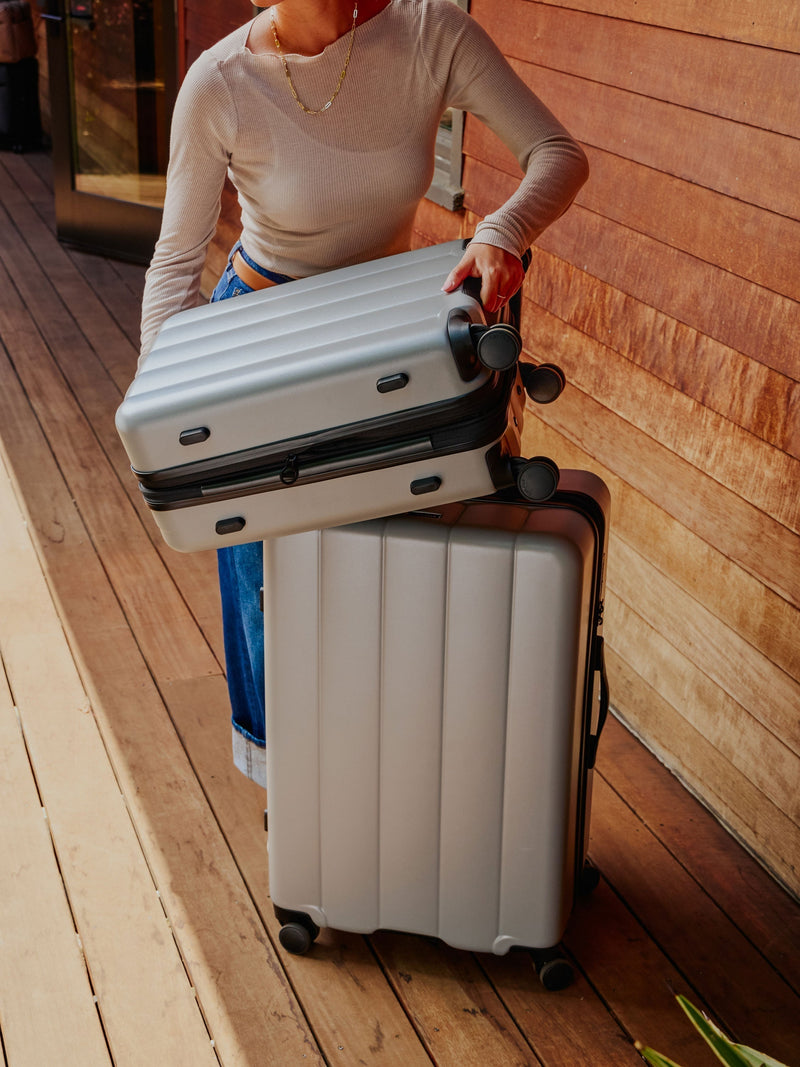 CALPAK Model displaying the Evry carry-on luggage and large luggage in gray smoke; LCO8000-SMOKE