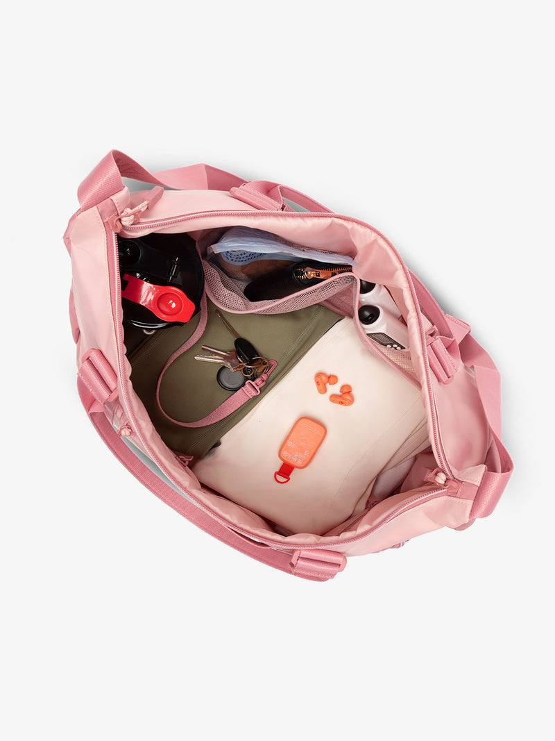 Interior view of tea rose pink CALPAK Fit Gym Bag with personal belongings packed within