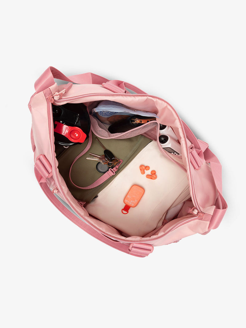 Interior view of tea rose pink CALPAK Fit Gym Bag with personal belongings packed within