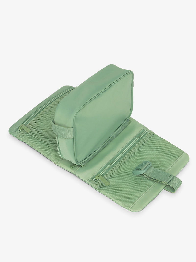 Flat lay of CALPAK Fit gym dopp kit with multiple interior mesh pockets in sage