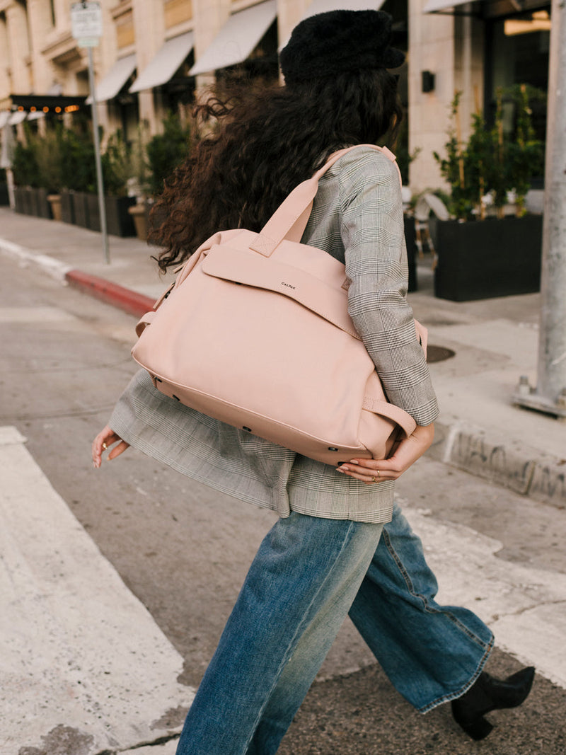 female model with faux leather pink sand CALPAK Hue duffel bag