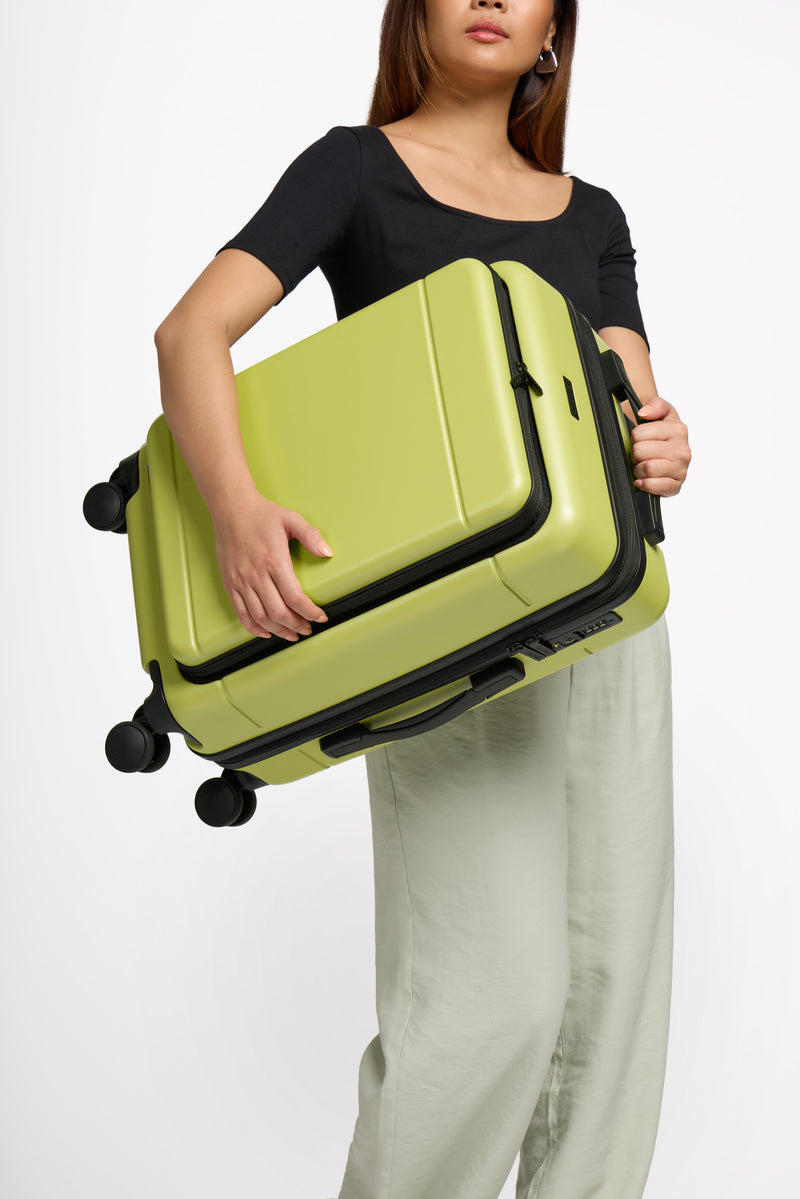 Model holding lightweight CALPAK Hue front pocket carry-on luggage