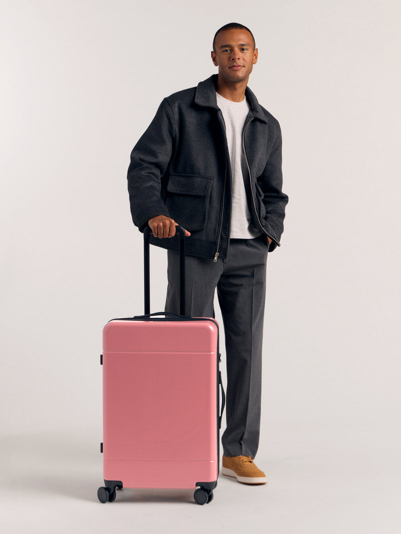 Model with CALPAK Hue Medium 26 inch Hardside Luggage in light pink mauve