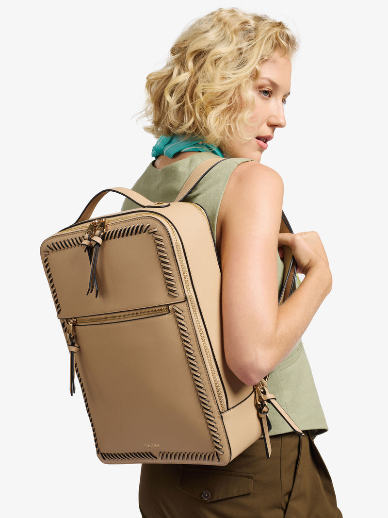 Model wearing latte CALPAK 15 inch laptop backpack with adjustable straps