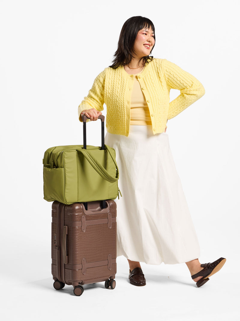 Model displaying luggage trolley sleeve of CALPAK Luka Duffel in pistachio; DSM1901-PISTACHIO