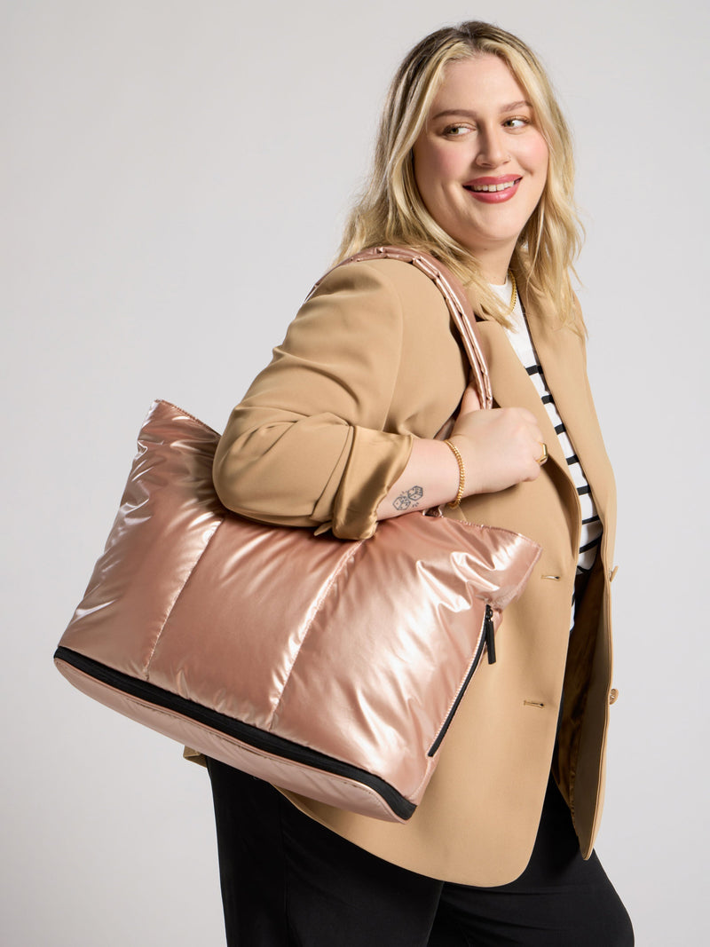 Model wearing luka expandable laptop tote over shoulder in metallic rose gold