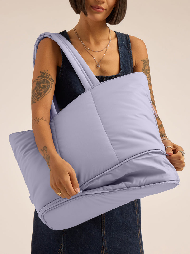 Model unzipping expandable portion of CALPAK Luka Expandable Tote in lavender purple Orchid