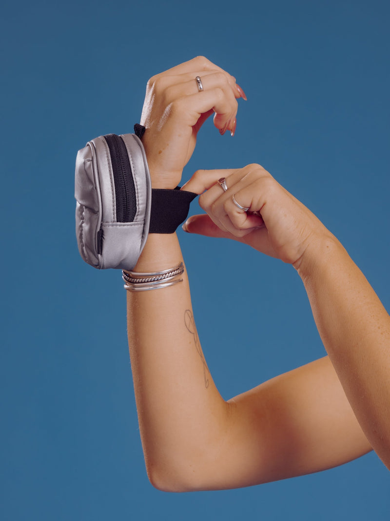 Model wearing gunmetal CALPAK Luka Key Pouch around wrist and displaying elastic wristband