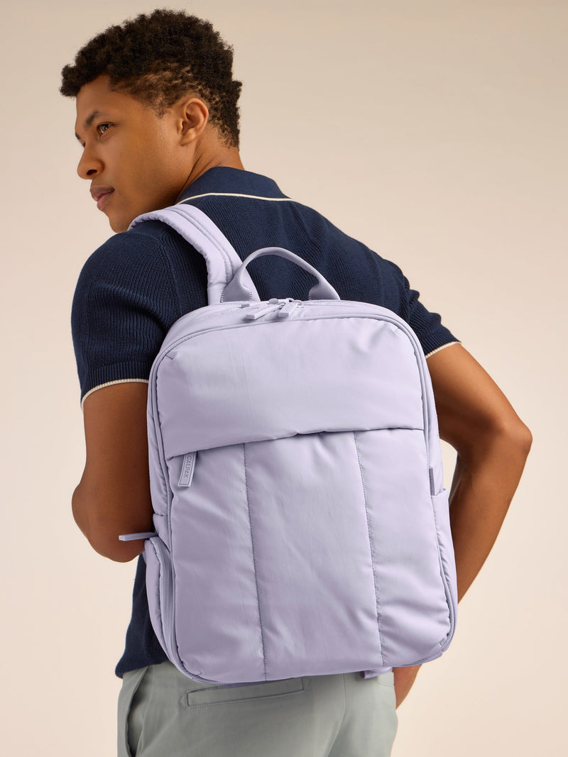 Model wearing CALPAK Luka 15 inch Laptop Backpack in lavender purple in Orchid