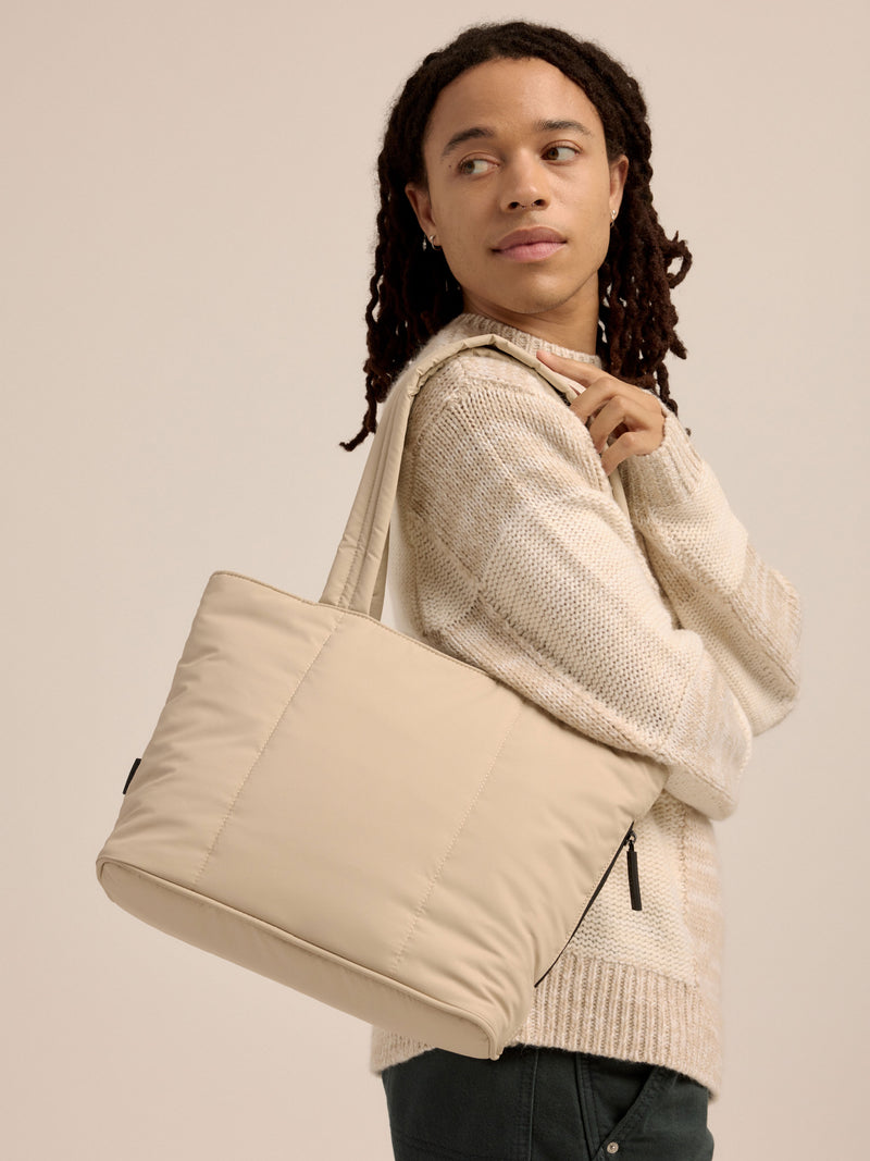 Model wearing soft, puffy CALPAK Luka Mini Tote over shoulder in beige oatmeal