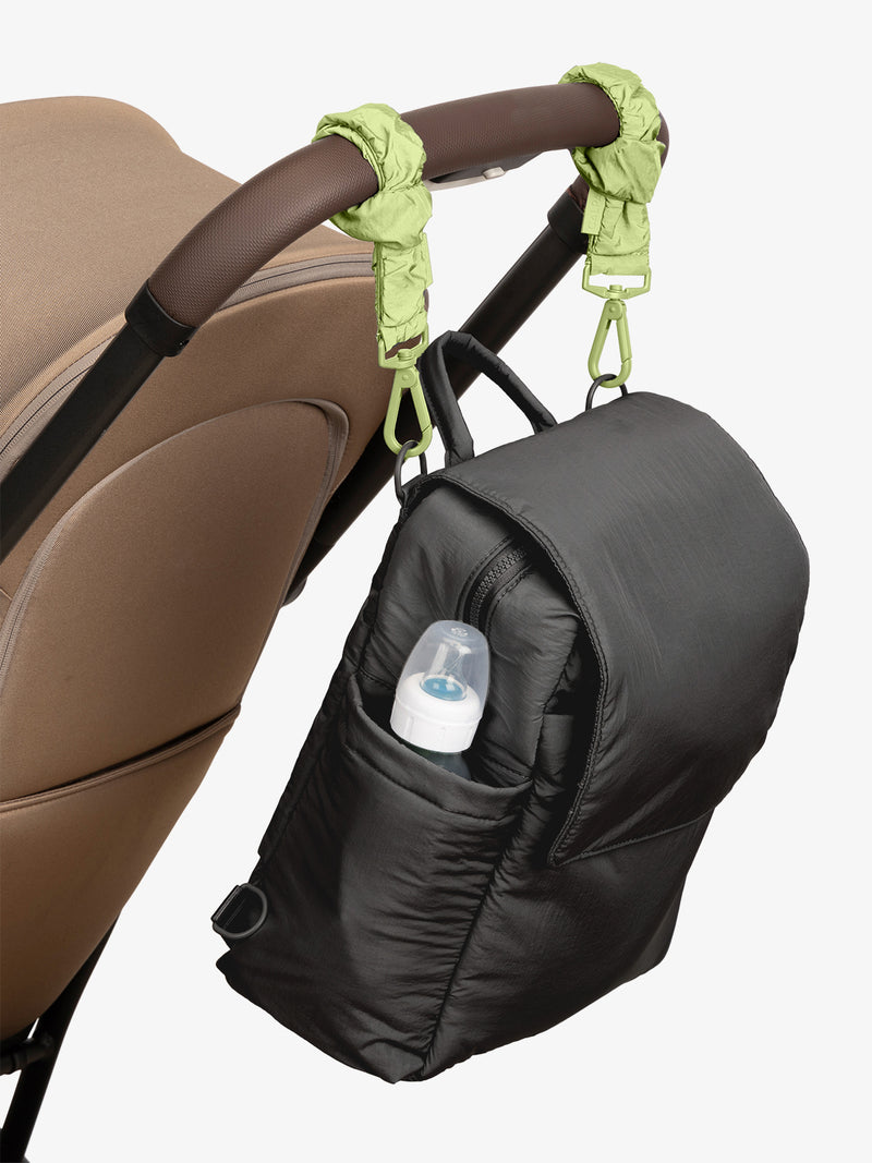 CALPAK Convertible Mini Diaper Backpack in Black with light green Lime Stroller Straps attached to a brown stroller