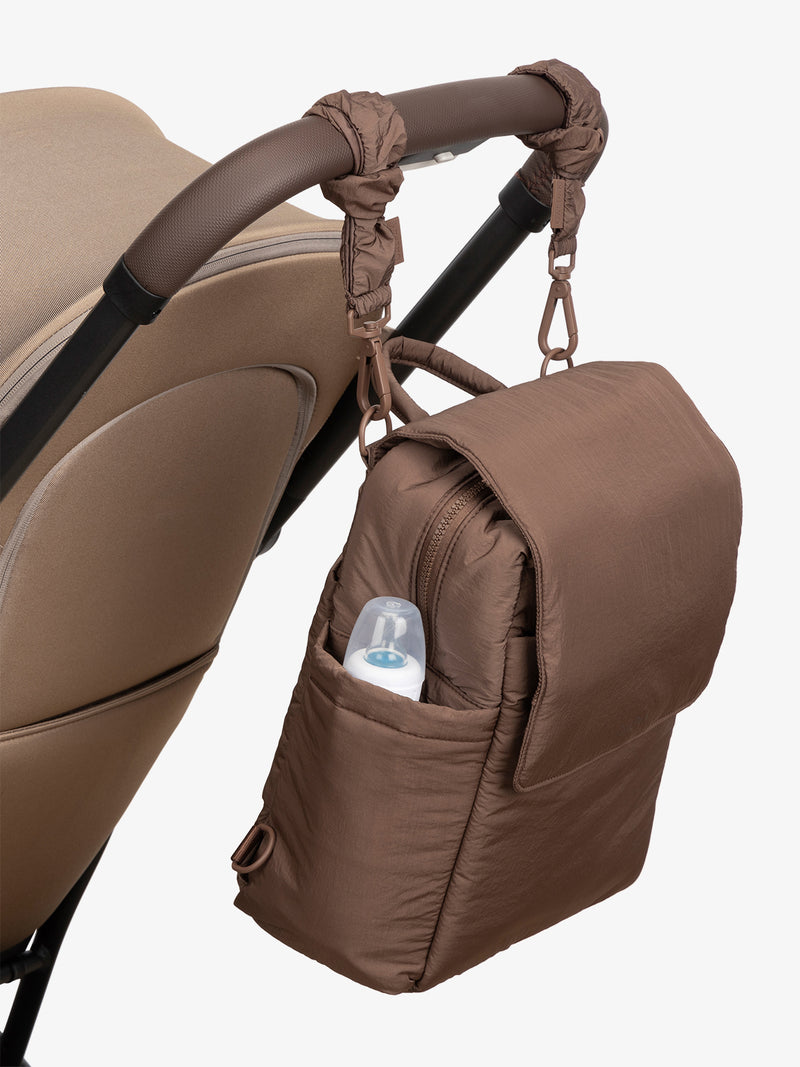 CALPAK Convertible Mini Diaper Backpack in brown Hazelnut with Brown Hazelnut Stroller Straps attached to a brown stroller