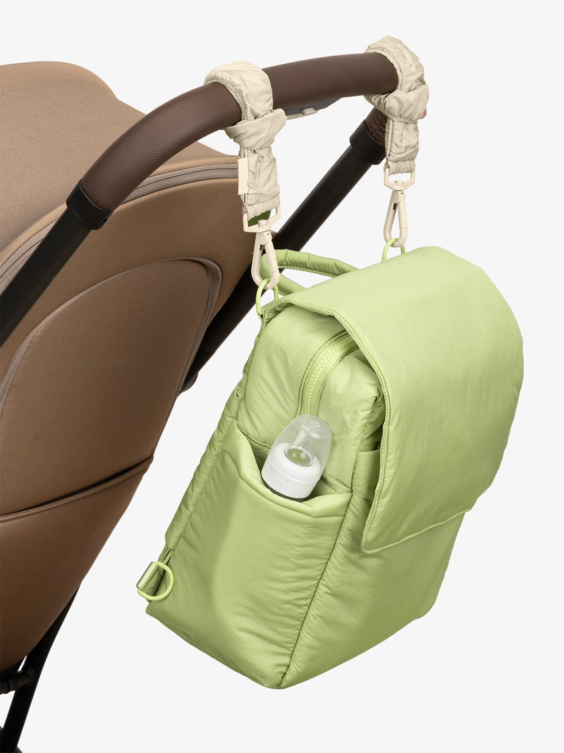 CALPAK Convertible Mini Diaper Backpack in light green Lime with white Oatmeal Stroller Straps attached to a brown stroller