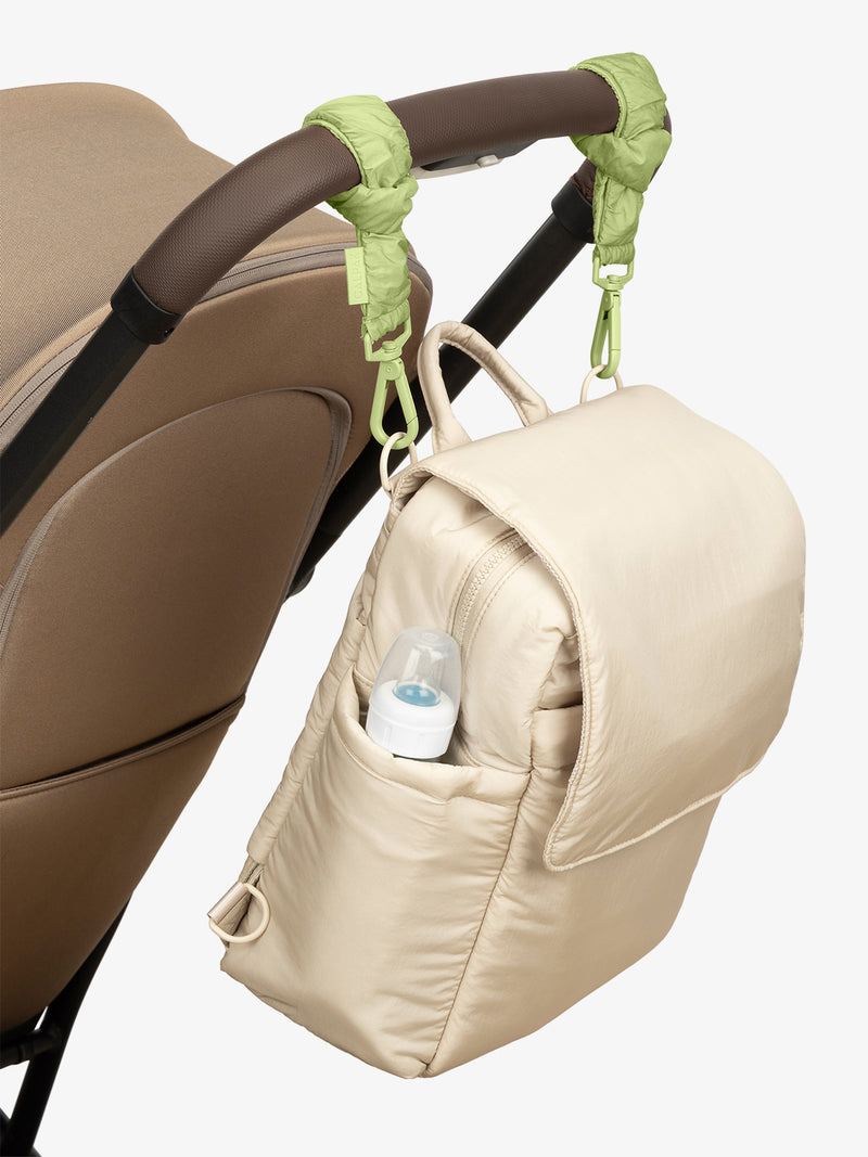 CALPAK Convertible Mini Diaper Backpack in white Oatmeal with light green Lime Stroller Straps attached to a brown stroller