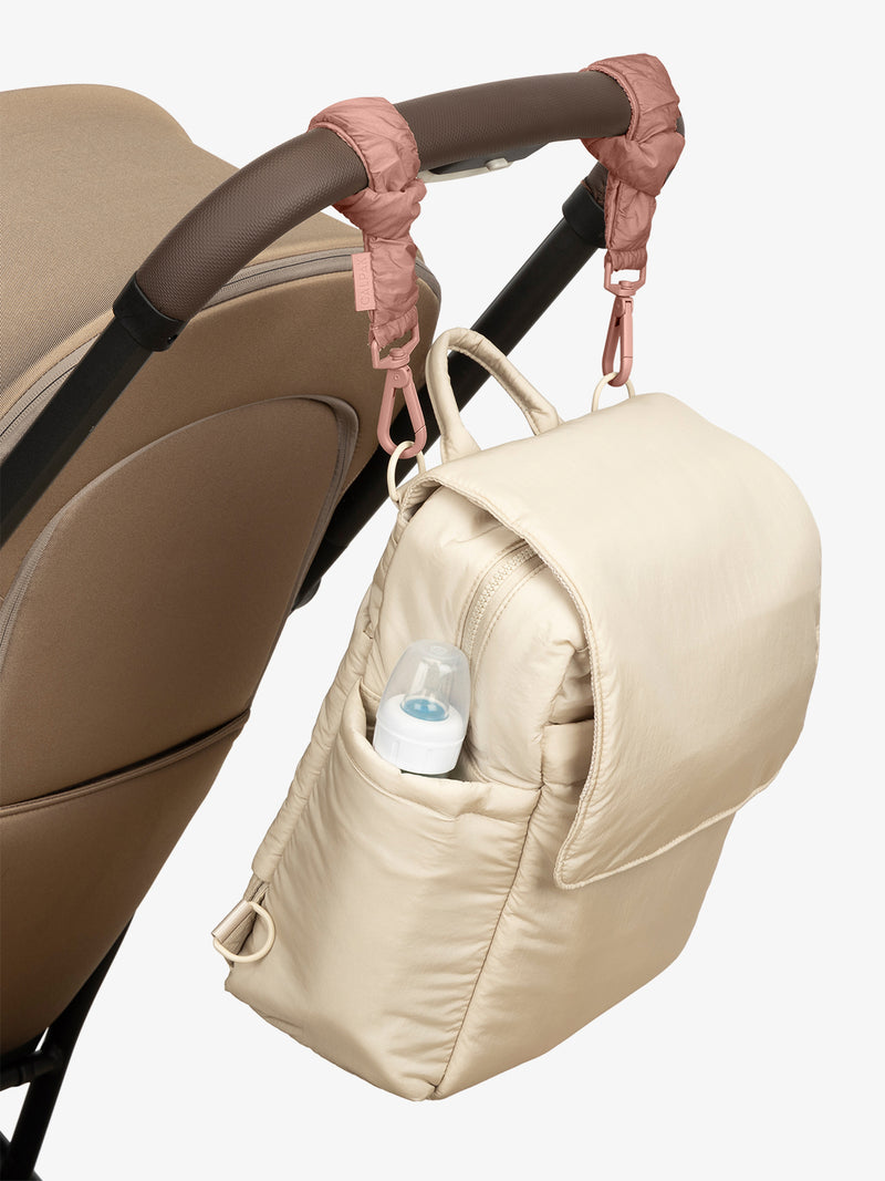 CALPAK Convertible Mini Diaper Backpack in white Oatmeal with pink Peony Stroller Straps attached to a brown stroller