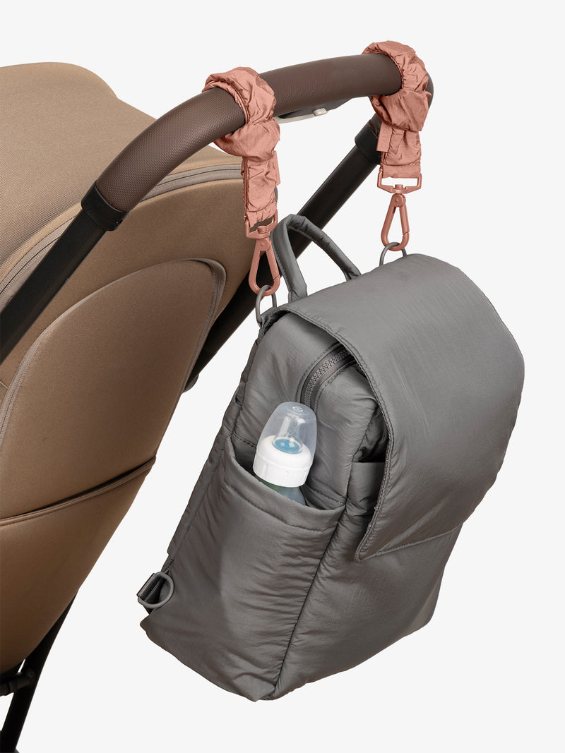 CALPAK Convertible Mini Diaper Backpack in grey Slate with pink Peony Stroller Straps attached to a brown stroller