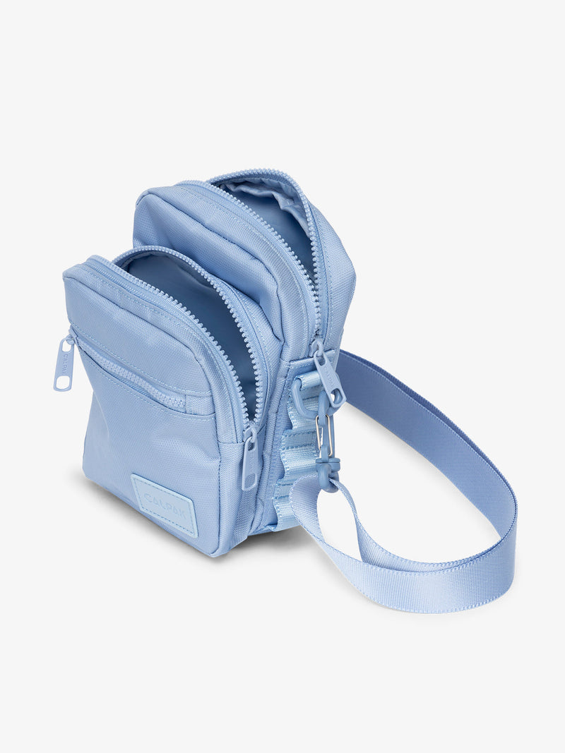 Baby blue CALPAK Stevyn Mini Crossbody Bag with adjustable shoulder strap, zippered pockets, and interior zipper pocket