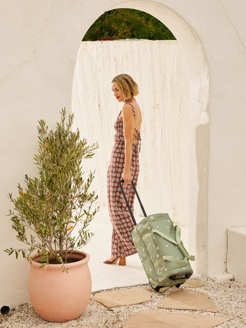 Model with CALPAK Stevyn Rolling Duffle bag with wheels in green floral print