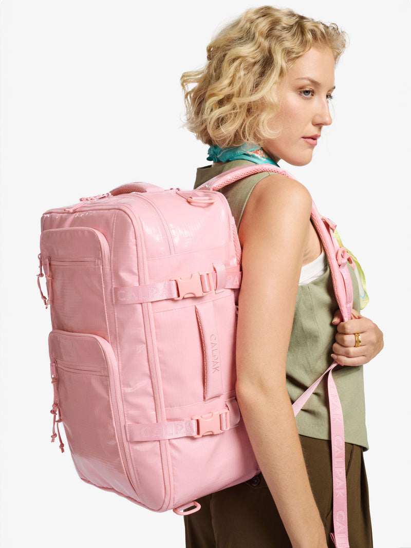 Model wearing CALPAK Terra 26L Laptop Duffel Backpack over shoulder by adjustable shoulder strap in pink